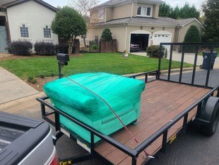 Wrapped couch on trailer being hauled away